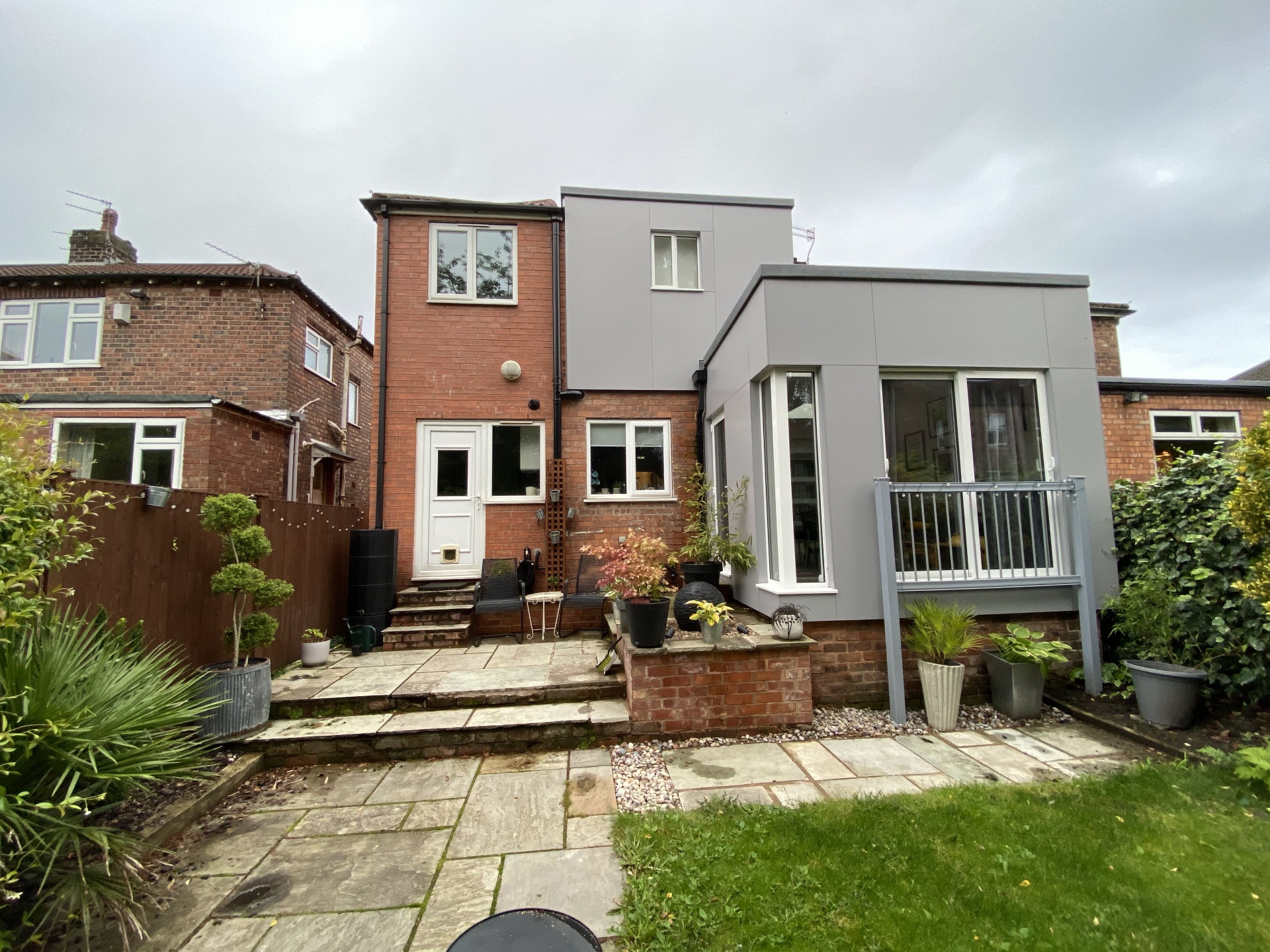 Completed rear extension with grey cladding, balcony detail and large corner glazing