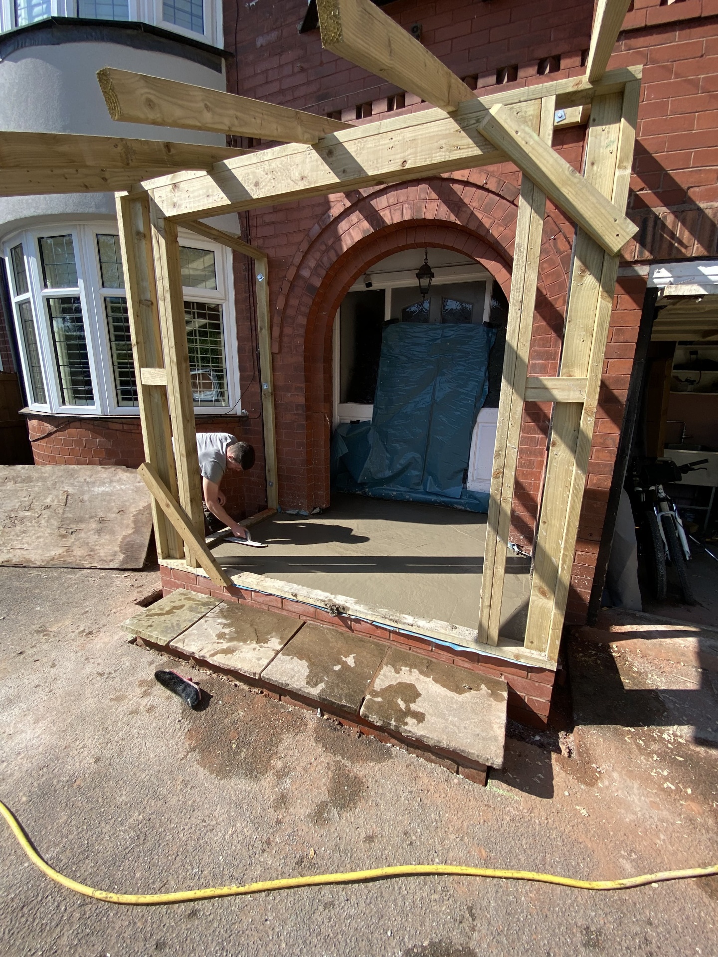 Front porch extension under construction with new timber framing, freshly screeded floor and original arched brickwork preserved