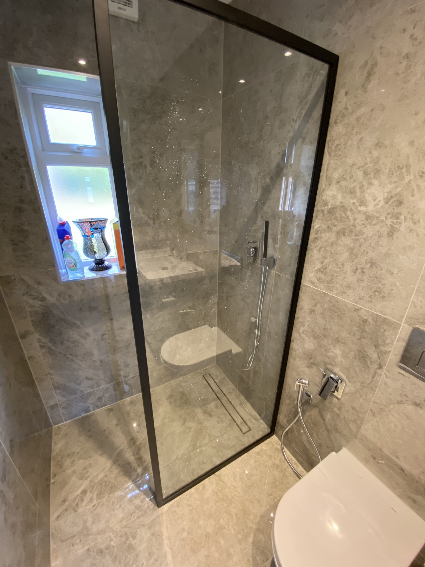 Completed bathroom with large-format tiles and walk-in shower area