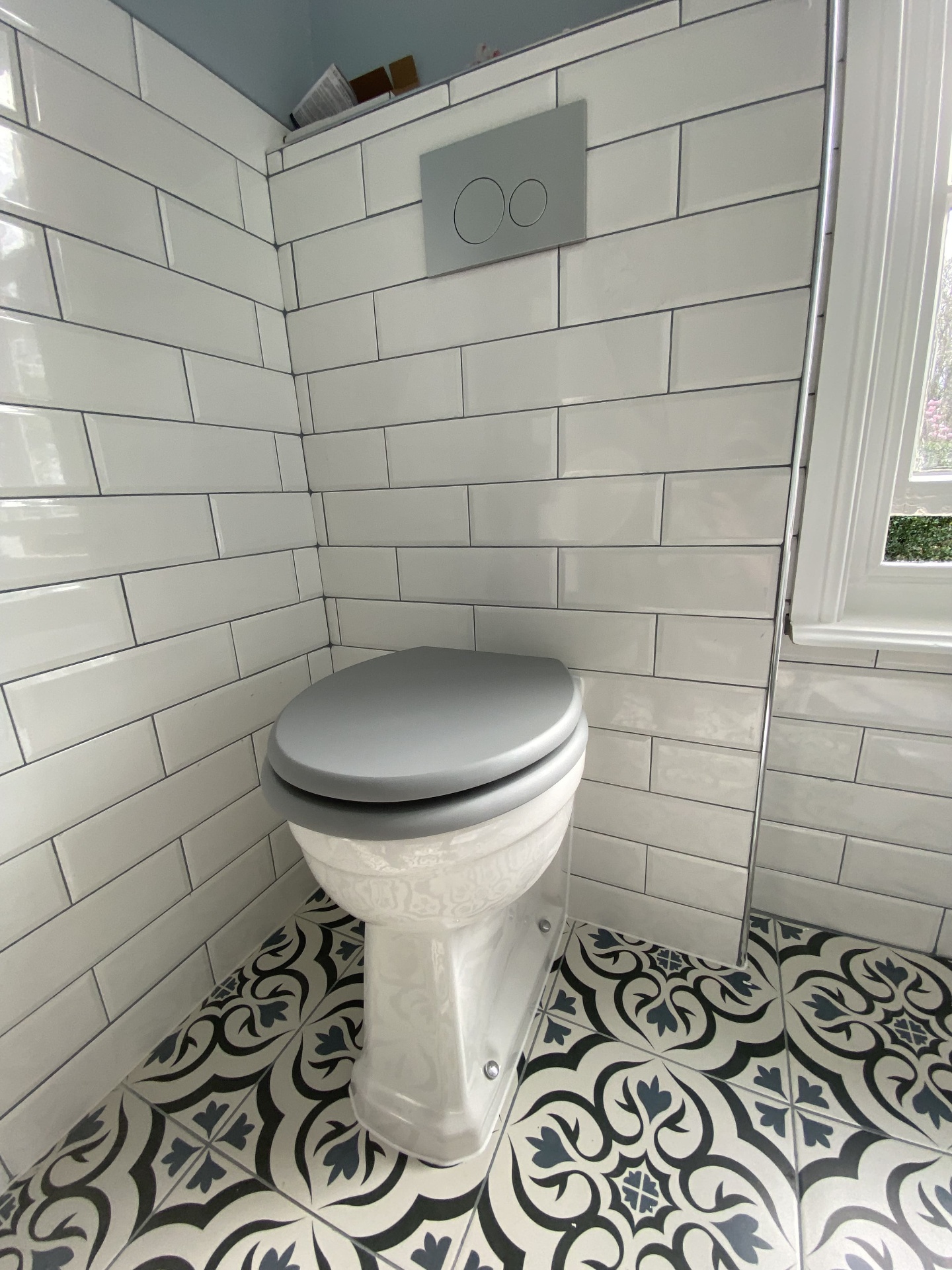 Completed cloakroom WC with white metro tiles and patterned floor tiling