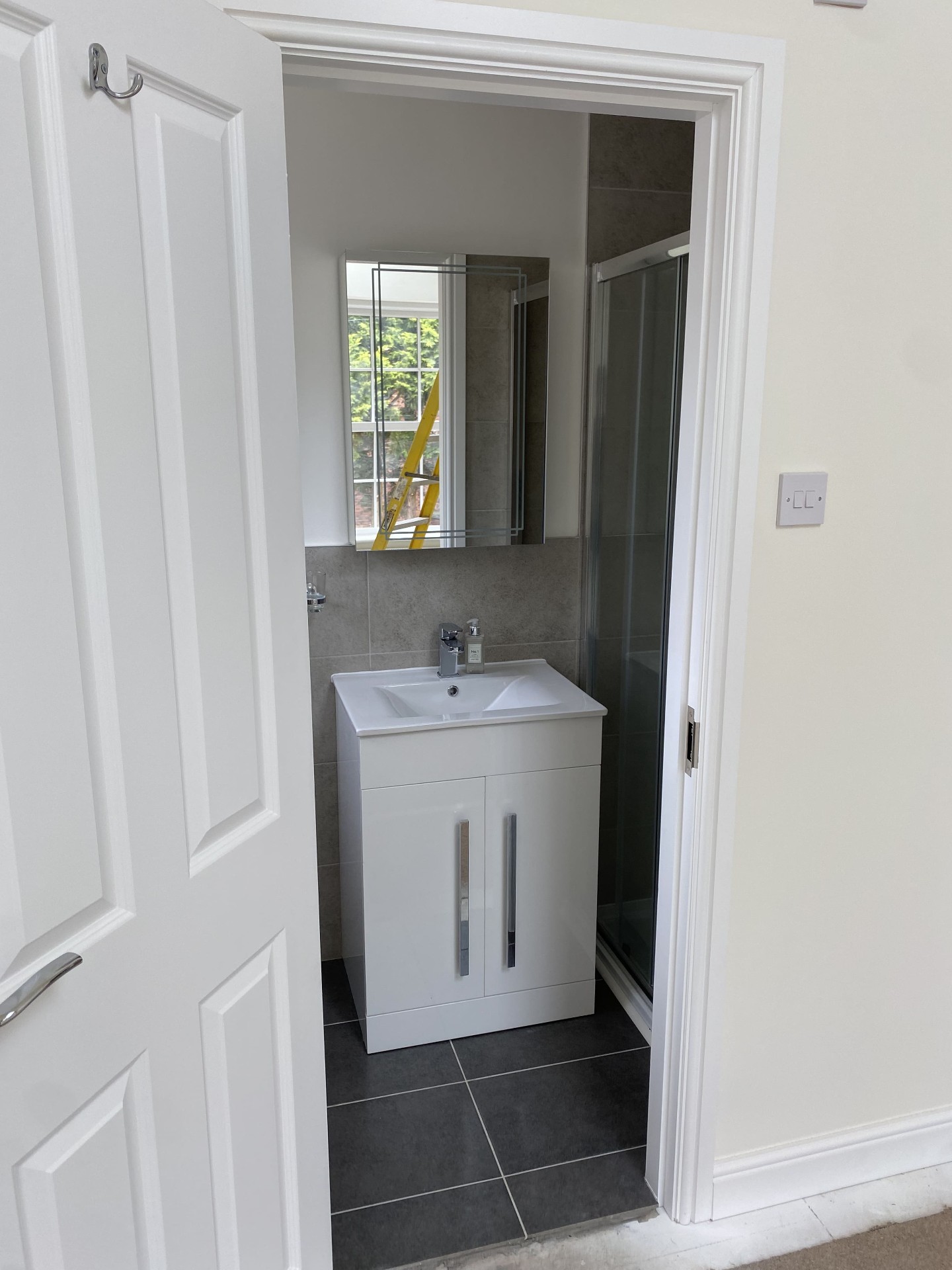 Completed compact bathroom with white vanity unit and walk-in shower enclosure