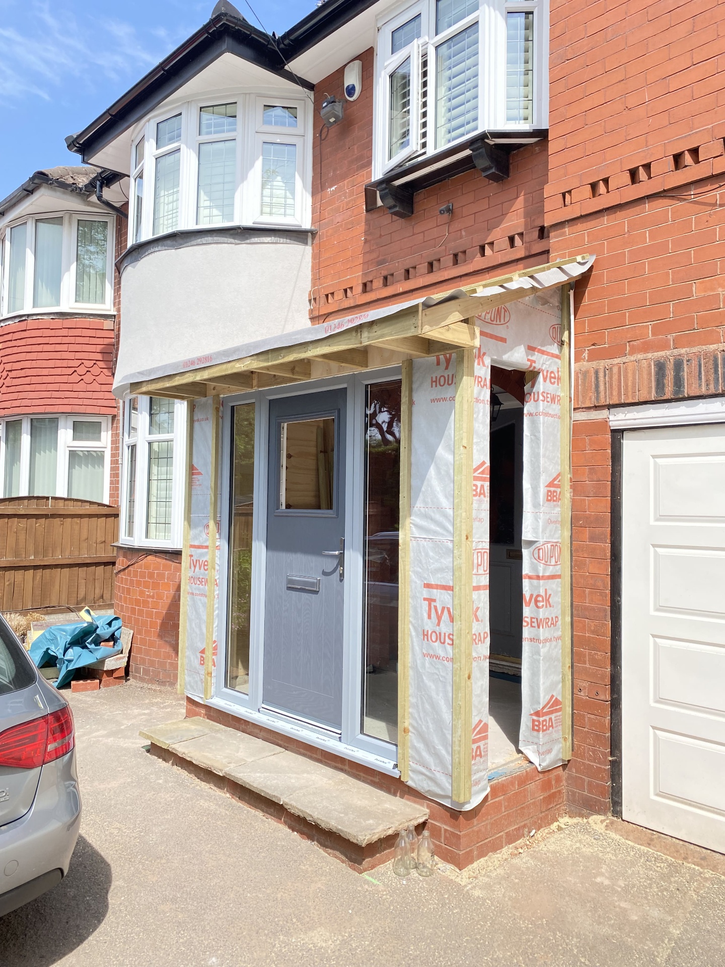 Front porch extension in progress with new composite door fitted and breathable membrane visible before brick finishing