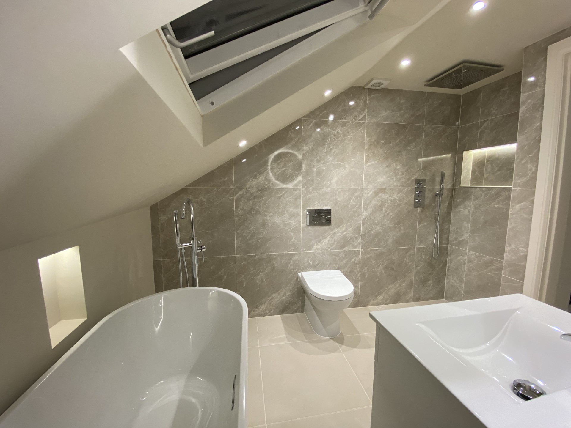 Completed bathroom featuring a freestanding bath and tiled surround
