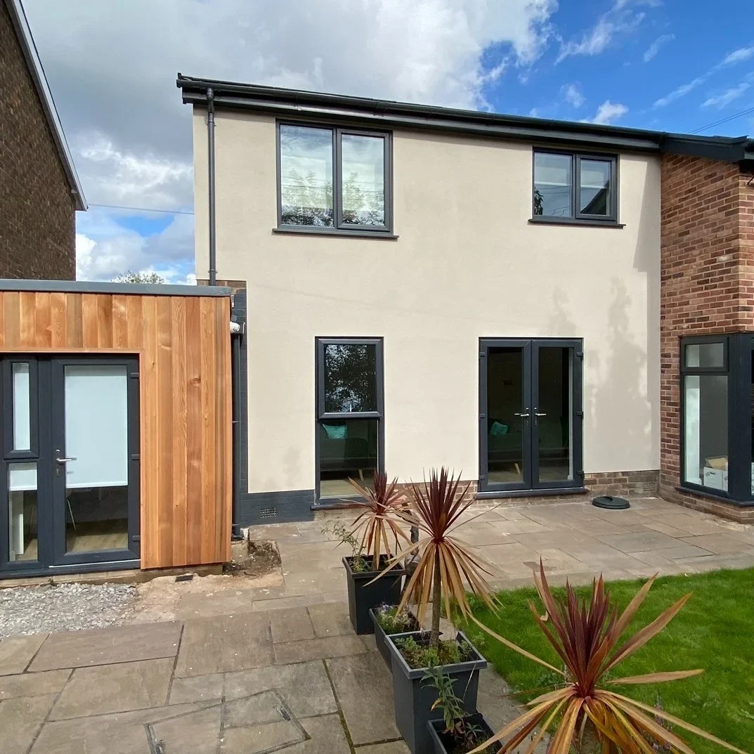 Completed rear extension with cedar cladding, anthracite French doors and rendered first-floor addition