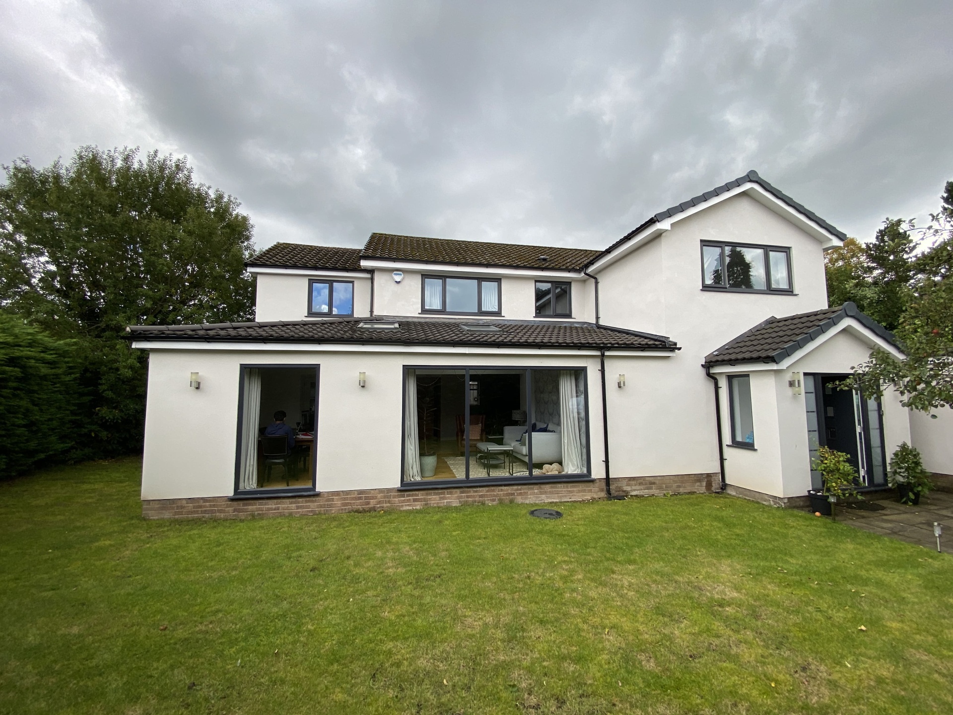 Completed rear elevation of a detached family home with rendered finish, sliding doors and landscaped lawn